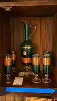Full set showing pedestal pitcher and five matching glasses in cabinet