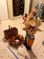 Scarecrow figures, basket, and wreath grouped on floor