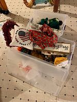 Two clear bins stacked with assorted pillows, garland, pumpkins and seasonal items