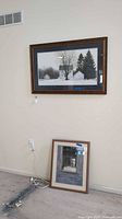 Wide view showing both framed prints, one wall-hung, one leaning