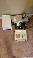 Printer, adapter, paper reams and cartridge pack on carpet