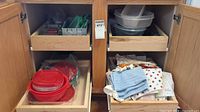 Cabinet drawers showing assorted plastic containers, bowls, towels