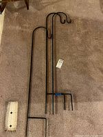 Two black metal shepherd hooks laid on carpet showing full length and curved hooks