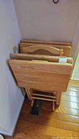 Four folded wood snack trays stored in matching stand