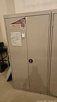 Front view of closed gray steel cabinet with handle