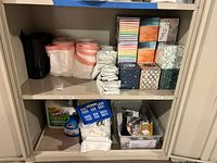 cabinet shelves holding trash bag rolls, tissue boxes, cleaning bottles, plastic bin with Q-Tips and Balmex