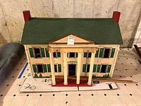 Front view showing full dollhouse with columns, roof, chimneys
