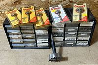 Two plastic drawer cabinets with labeled drawers, four packaged Freud bits on top, loose large Forstner bit in front