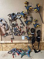 Overall view of pegboard with majority of clamps plus additional clamps on floor