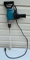 Full view of Makita drill with attached mixer paddle and power cord