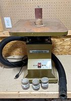 Full view of Powermatic oscillating spindle sander, mounted sleeve, dust hose, three spare sleeves