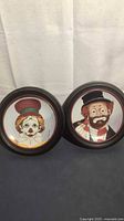 Both framed decorative clown plates side by side