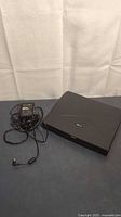 Closed Acer Extensa 710DX with power adapter and cord