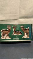 Front of box displaying three reindeer figurines in window