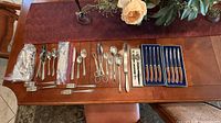 Overall view of assorted flatware laid out on table, steak knives boxed at right