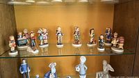 Full view of all 13 figurines on glass shelf