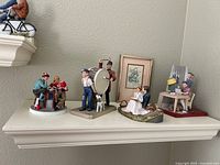Front view of all four figurines and framed print on shelf