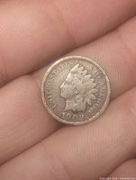 Obverse of 1902 Indian Head cent held between fingers