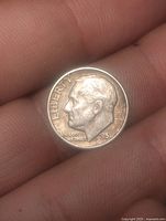 Obverse of 1957 Roosevelt dime in hand showing date and condition
