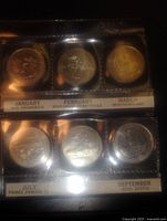 Reverse views showing five labelled coins in plastic sleeve