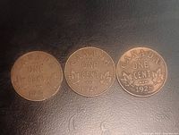 Reverse of three Canadian one-cent coins showing years 1935, 1929, 1928