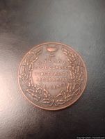 Obverse of copper medal showing inscription and wreath