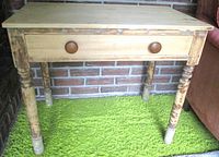 Front view of wooden table showing drawer, knobs, legs