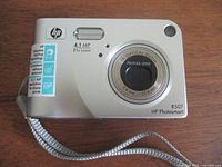Front view HP PhotoSmart R607 camera showing lens, 4.1MP 21x zoom markings and wrist strap