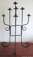 Front view of fully opened seven-arm wrought iron candelabra showing all candle plates