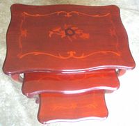 Top view of stacked rosewood nesting tables showing marquetry inlay and lacquered finish