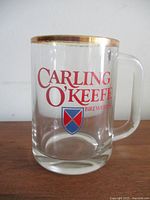 Front view showing Carling O'Keefe logo, gold rim, handle profile