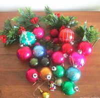 Group of assorted glass ornaments with faux holly sprigs