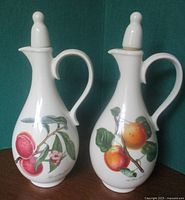 Front view of both porcelain cruets showing fruit designs and stoppers