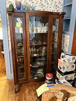 Full view of dark wood curio cabinet with glass doors and contents inside