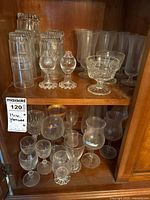 Cabinet shelves showing assorted clear glass stemware grouped together