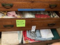 Drawer with multiple folded linens, visible clover motif, pink napkin stack