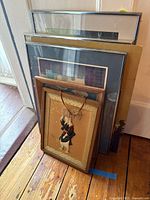 Stack of framed artworks showing variety of frames and Asian figure piece