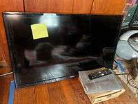 Front view of TV with remote and manual
