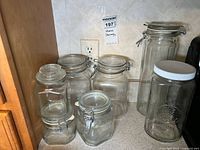 All six glass jars grouped on countertop showing shapes, lids, and size differences
