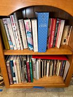 Full shelf view showing two rows of assorted vintage cookbooks, binders and spiral volumes