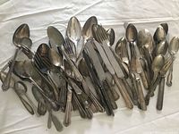 Overview of piled silverplate flatware on white cloth