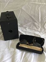 Kodak Brownie box camera beside open spectacles case displaying glasses