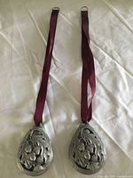 Two pewter ornaments front view showing relief pattern and ribbons