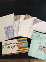 all items laid out: oil pastels box, tracing paper pad, stack of canvas panels