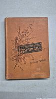Front cover of brown cloth hardcover book with floral design and title