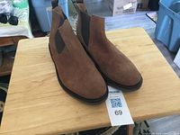 Full view of both brown suede ankle boots on table