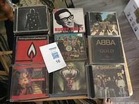 Nine CDs laid flat showing several titles and MaxSold lot card