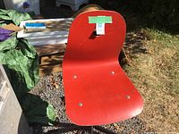 Front view of red molded plywood chair showing seat, back, and wear