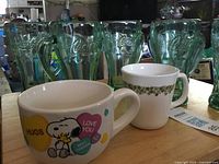 Group showing eight green Coca-Cola tumblers with two ceramic mugs in front