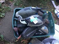Top view of green tote filled with various plastic duck decoys showing weighted keels and paint condition